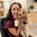 female veterinarian with long dark hair holding a Yorkie